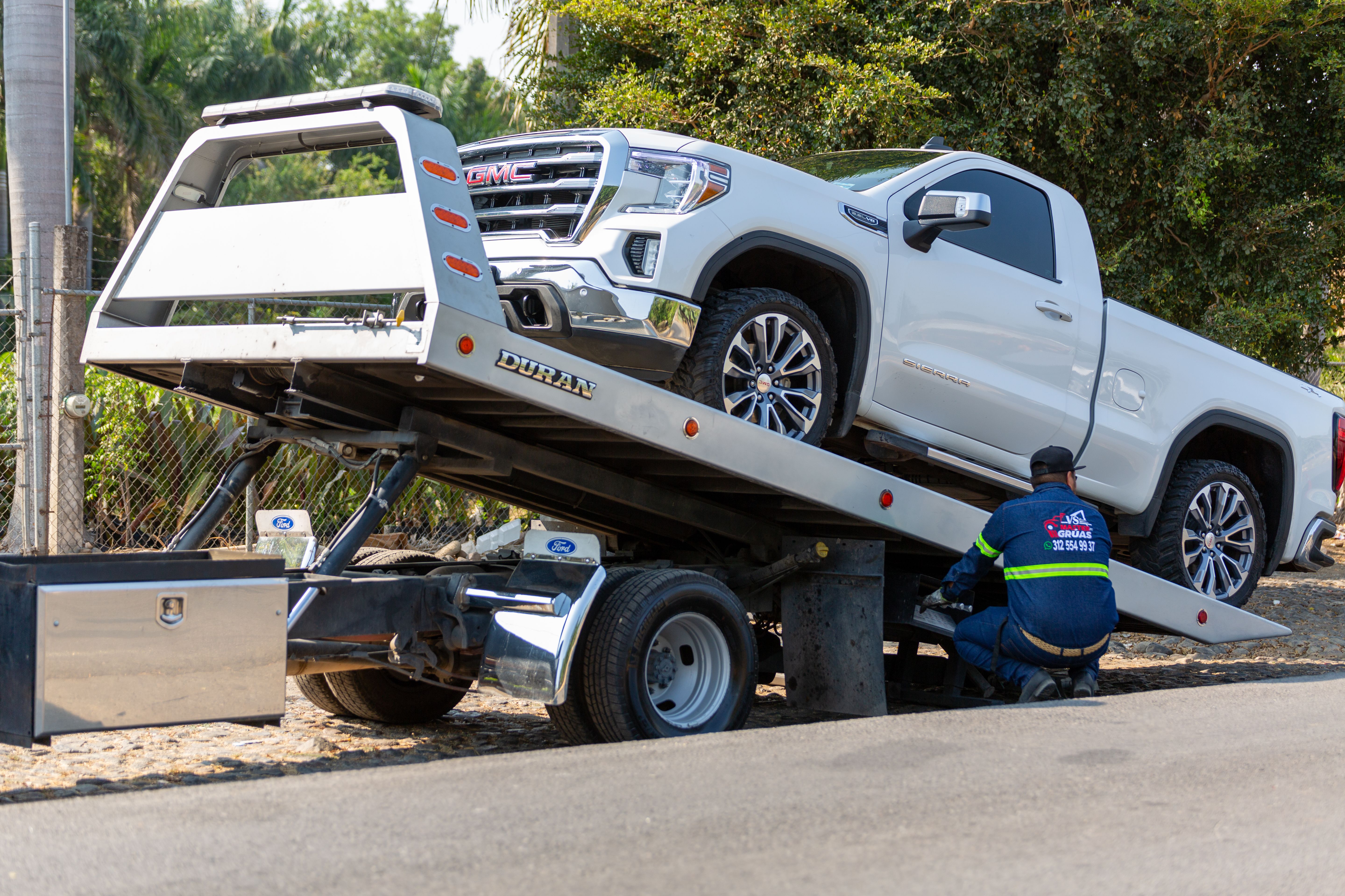 Tow truck operator loading a broken-down truck after a roadside breakdown