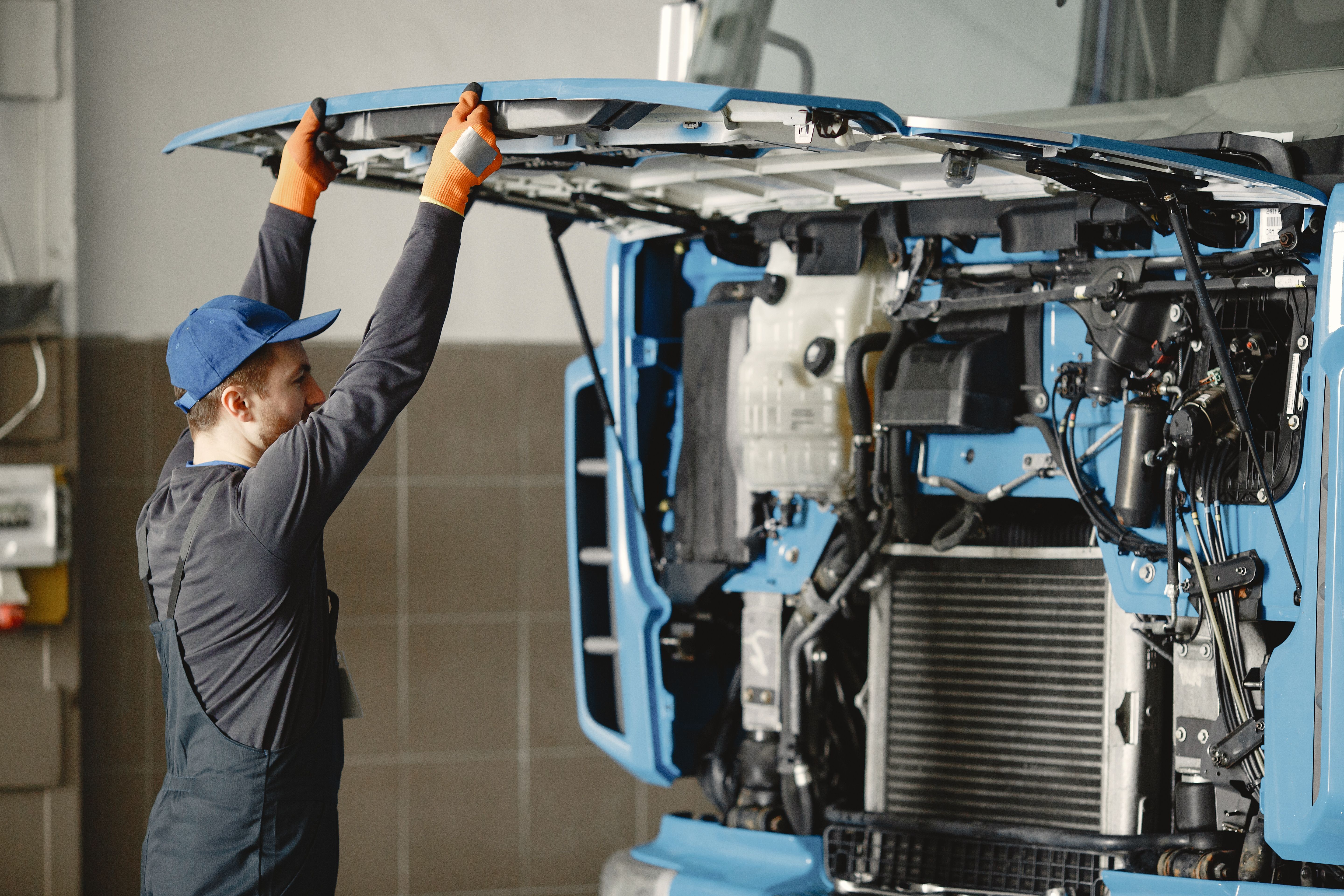 Mechanic in uniform inspecting a heavy-duty truck engine for maintenance issues